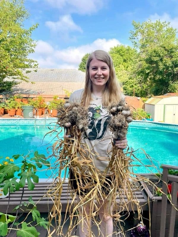 Liz holding a garlic harvest from her garden